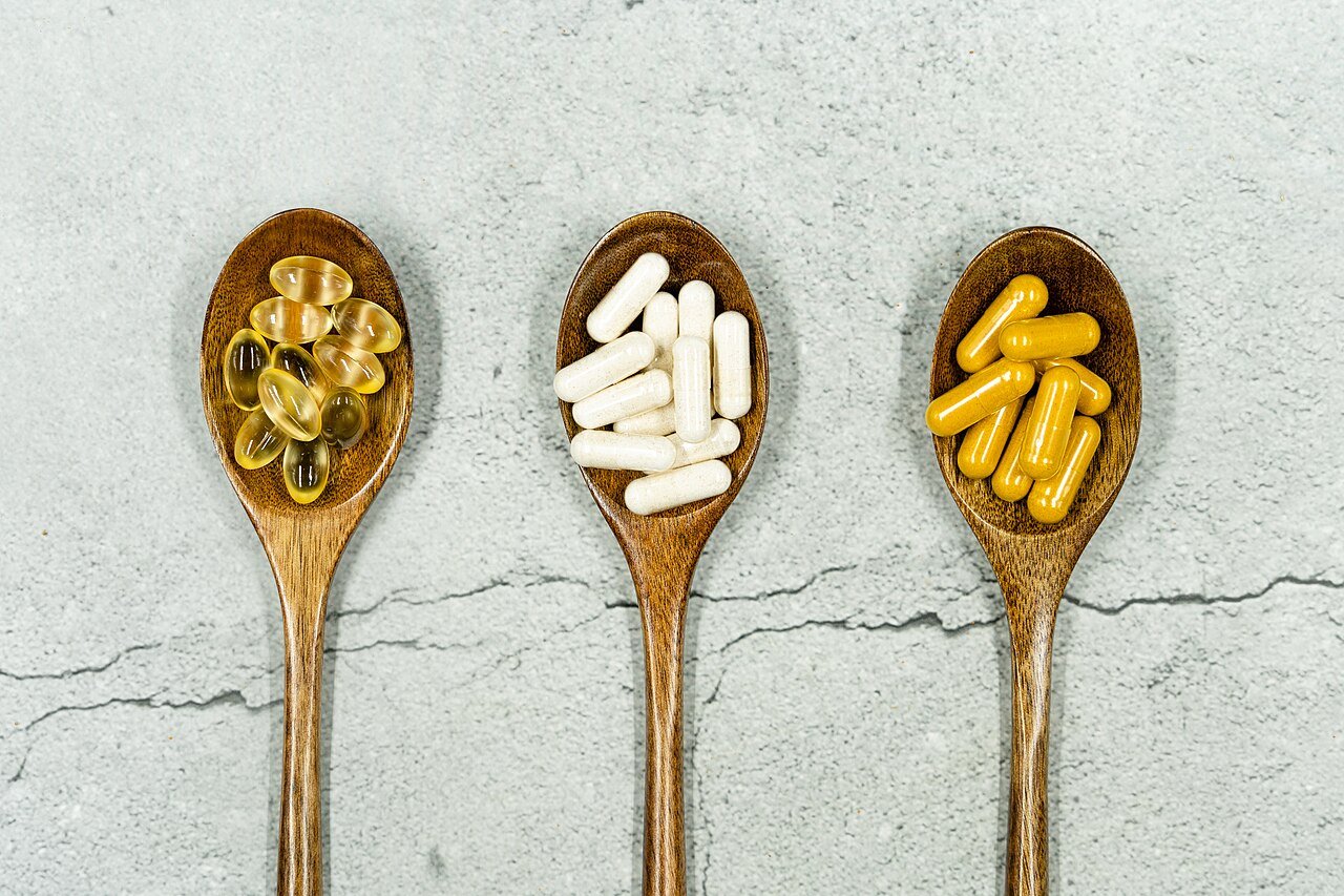 Assorted dietary supplement capsules on wooden spoons, representing joint health ingredients